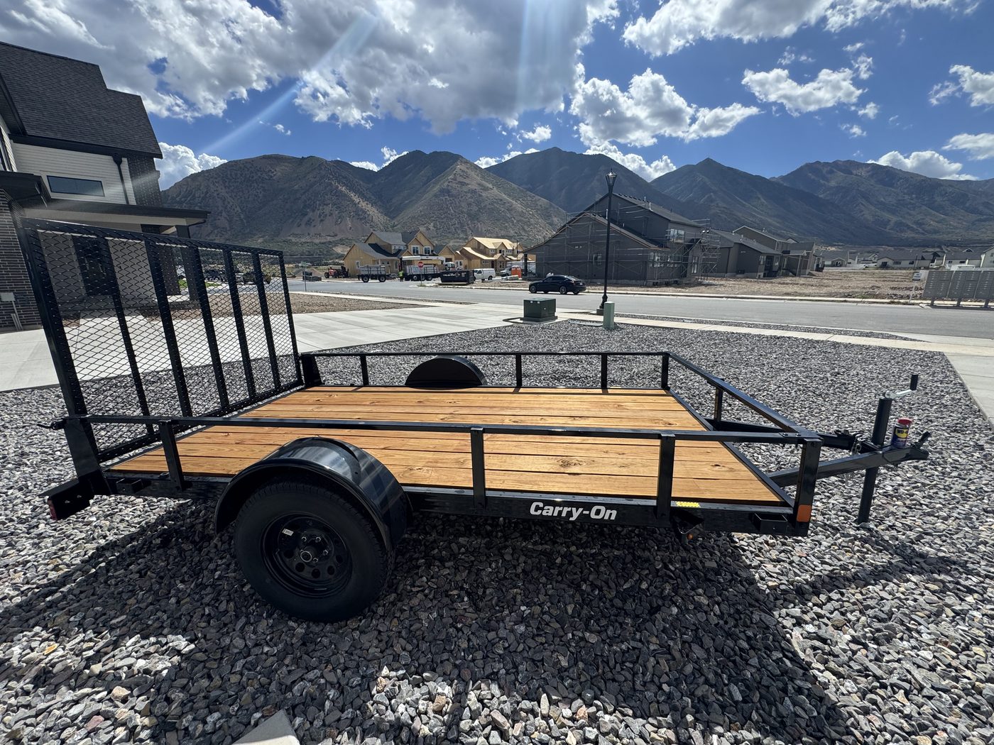 Full side view of the 2026 Carry-On 6x11 utility trailer with sides up, showing the tongue, wheel and rear gate